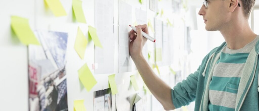 man writing digital marketing ideas on post -it notes